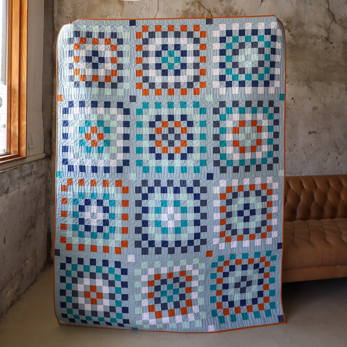 front view of full blue, orange, and white Campfire Granny Patch quilt in studio