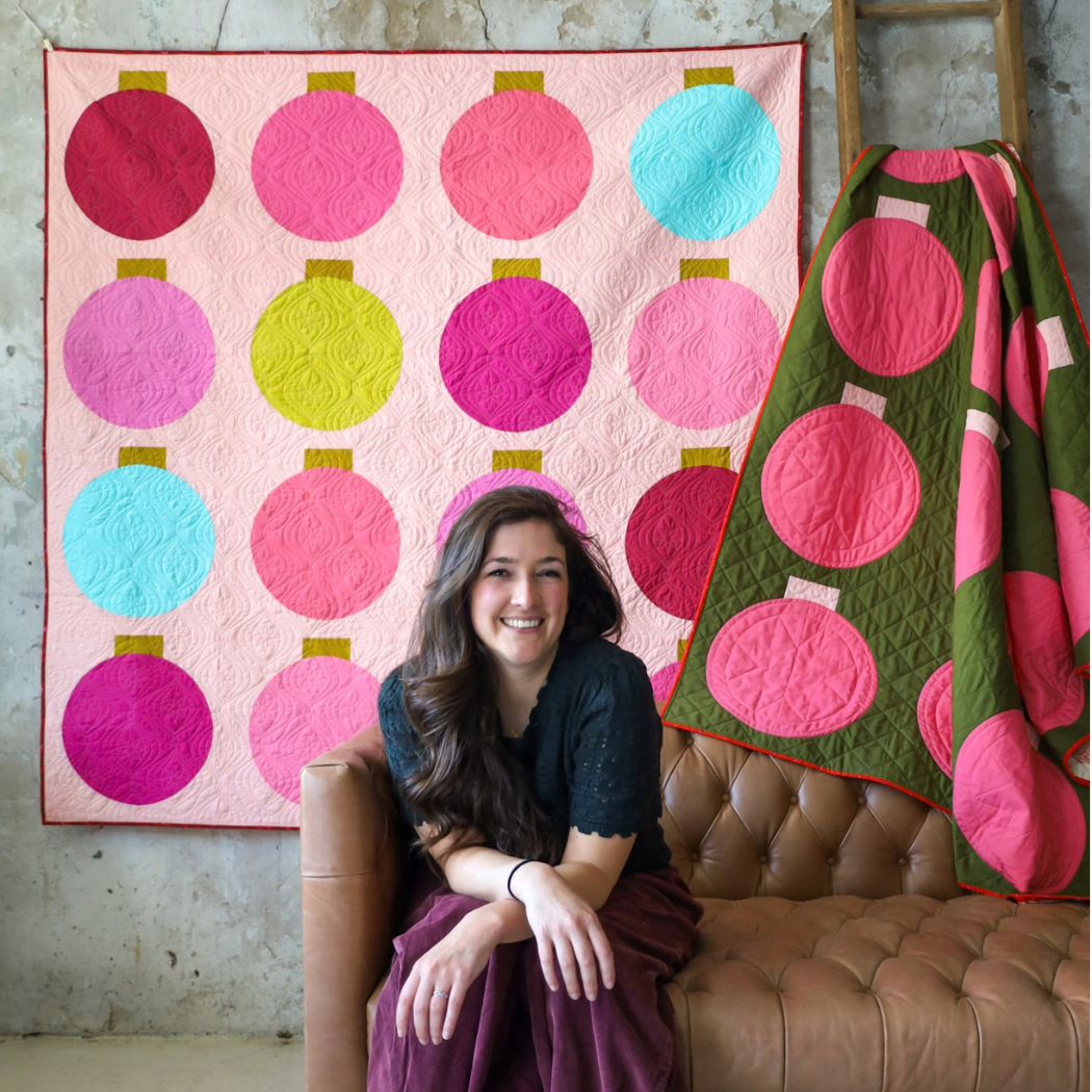 Retro Ornaments quilt hanging on studio wall behind a Christmas tree