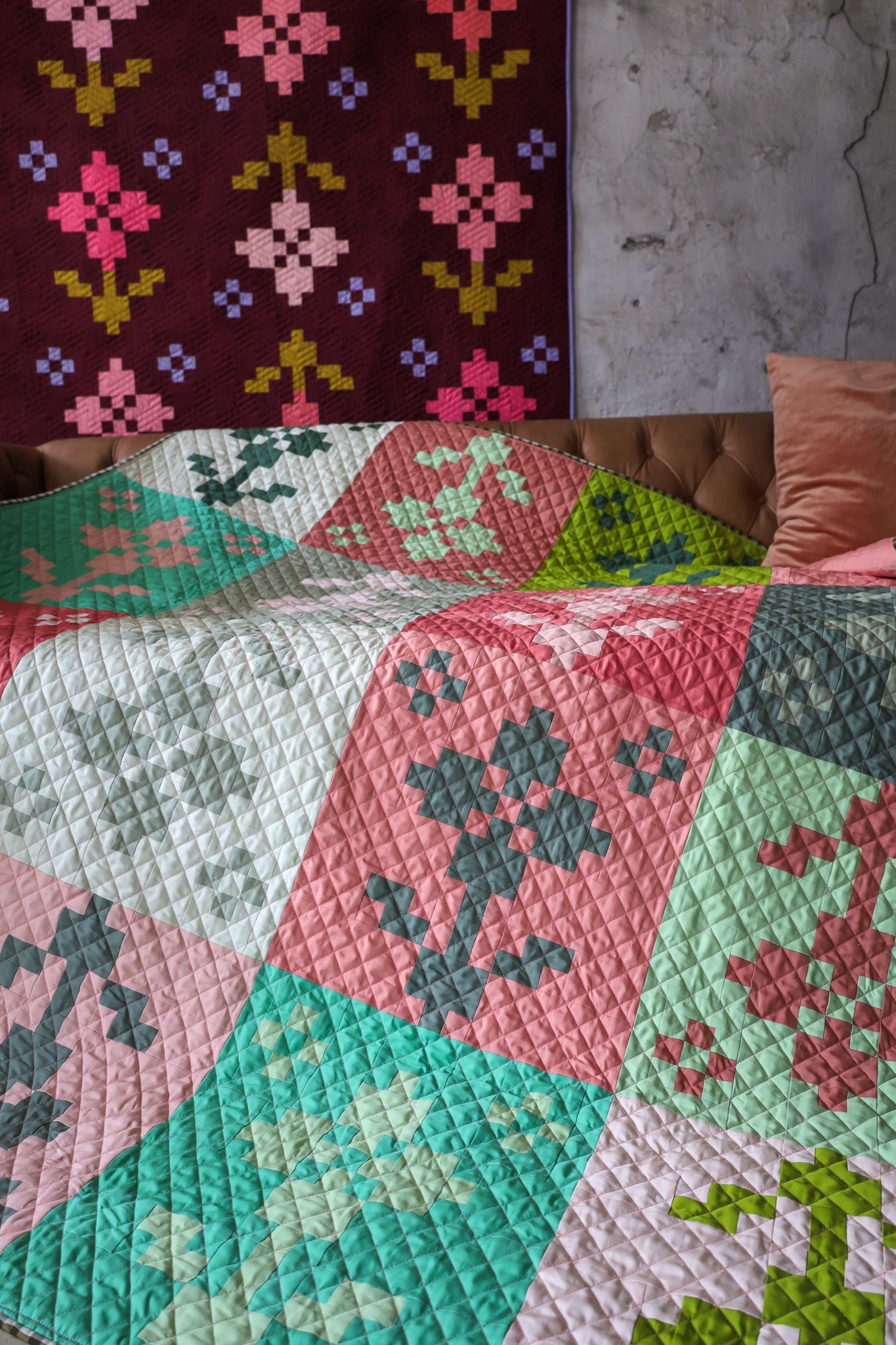 Pansy Patch quilt samples hanging on a wall and lying on a couch
