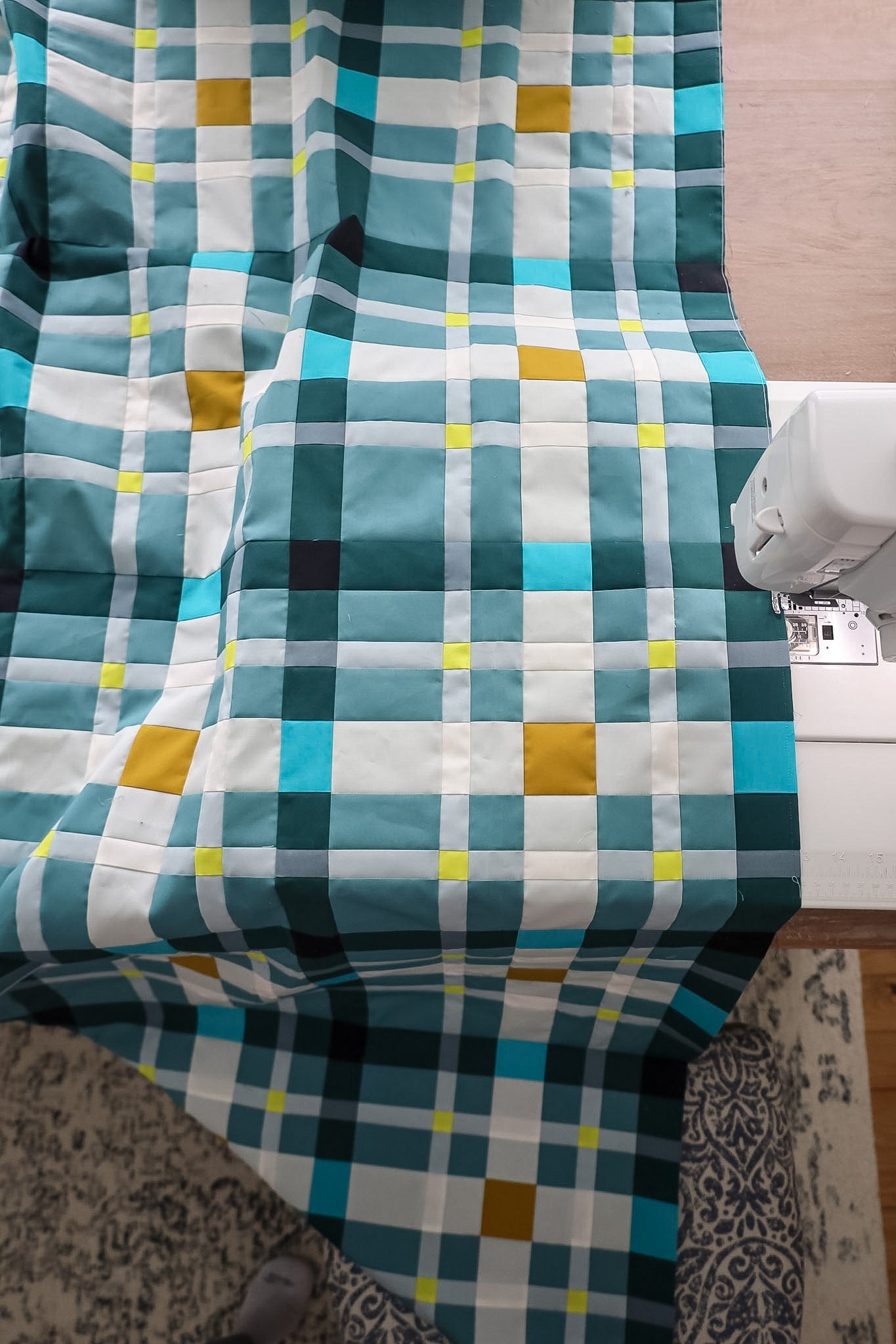 Petite Plaid Wintergreen sample quilt on a table with sewing machine