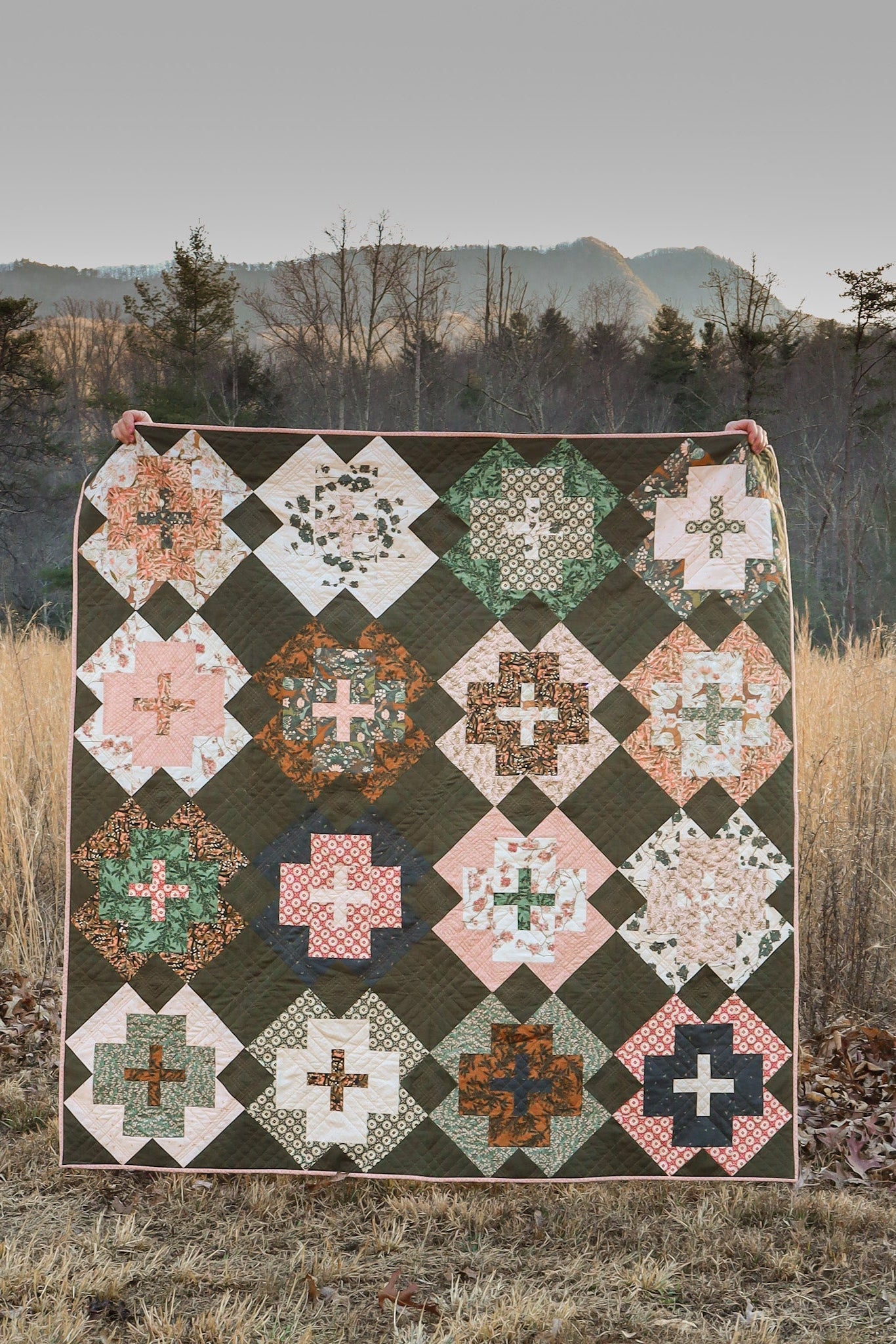 Nightingale Botanist square throw size quilt sample featuring "Botanist" collection by Katarina Roccella for Art Gallery Fabrics held up in a field. 